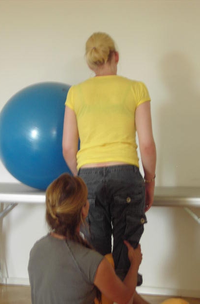 Neurophysiologische Bewegungstherapie Eine junge Frau stützt sich auf dem Behandlungsbett auf